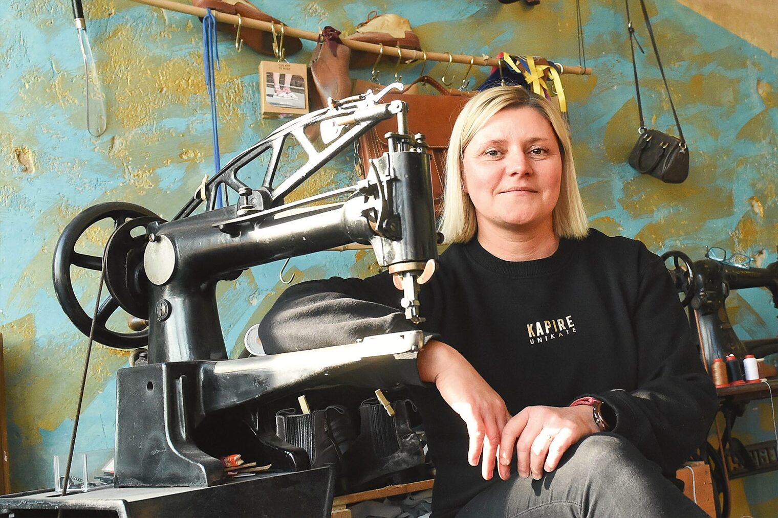 Schuhmacherin Karina Ranft sitzt neben einer alten Nähmaschine aus Museumsbestand