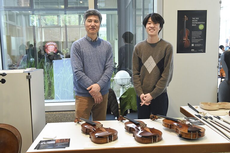 Zwei Geigenbauer präsentieren ihre Instrumenten an ihrem Stand