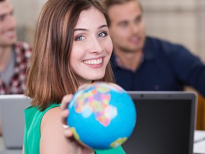 Lernen und arbeiten im Ausland während der Ausbildung. Junge Frau mit Globus in der Hand.