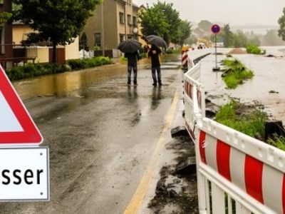 Hochwasser nach Starkregen und Schild mit Hinweis auf Hochwasser