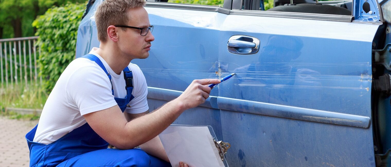 Sachverständiger im Handwerk untersucht Schaden an Auto und erstellt Gutachten.