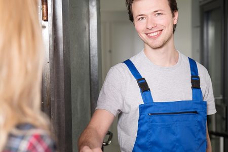 Handwerker im Blaumann begrüßt Kundin