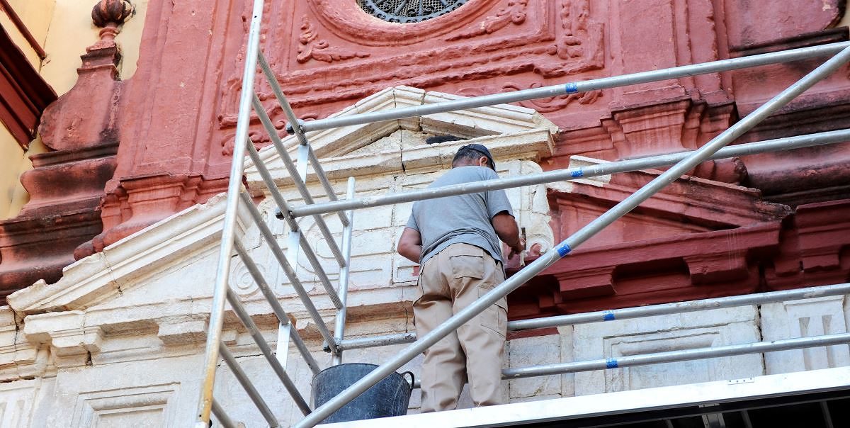 Restaurierung einer Kirchenfassade Denkmalpflege, Restaurierung. Mann auf Gerüst restauriert Fassade einer Kirche.