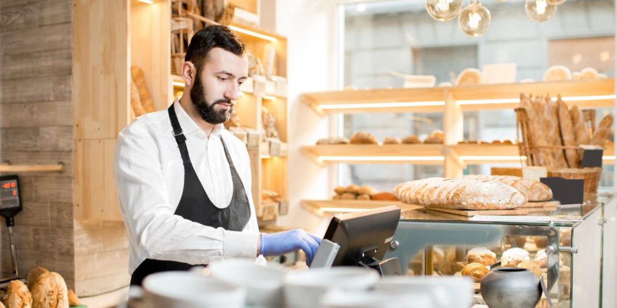 Bäckerei-Verkäufer gibt Geldbetrag in Kassensystem ein.