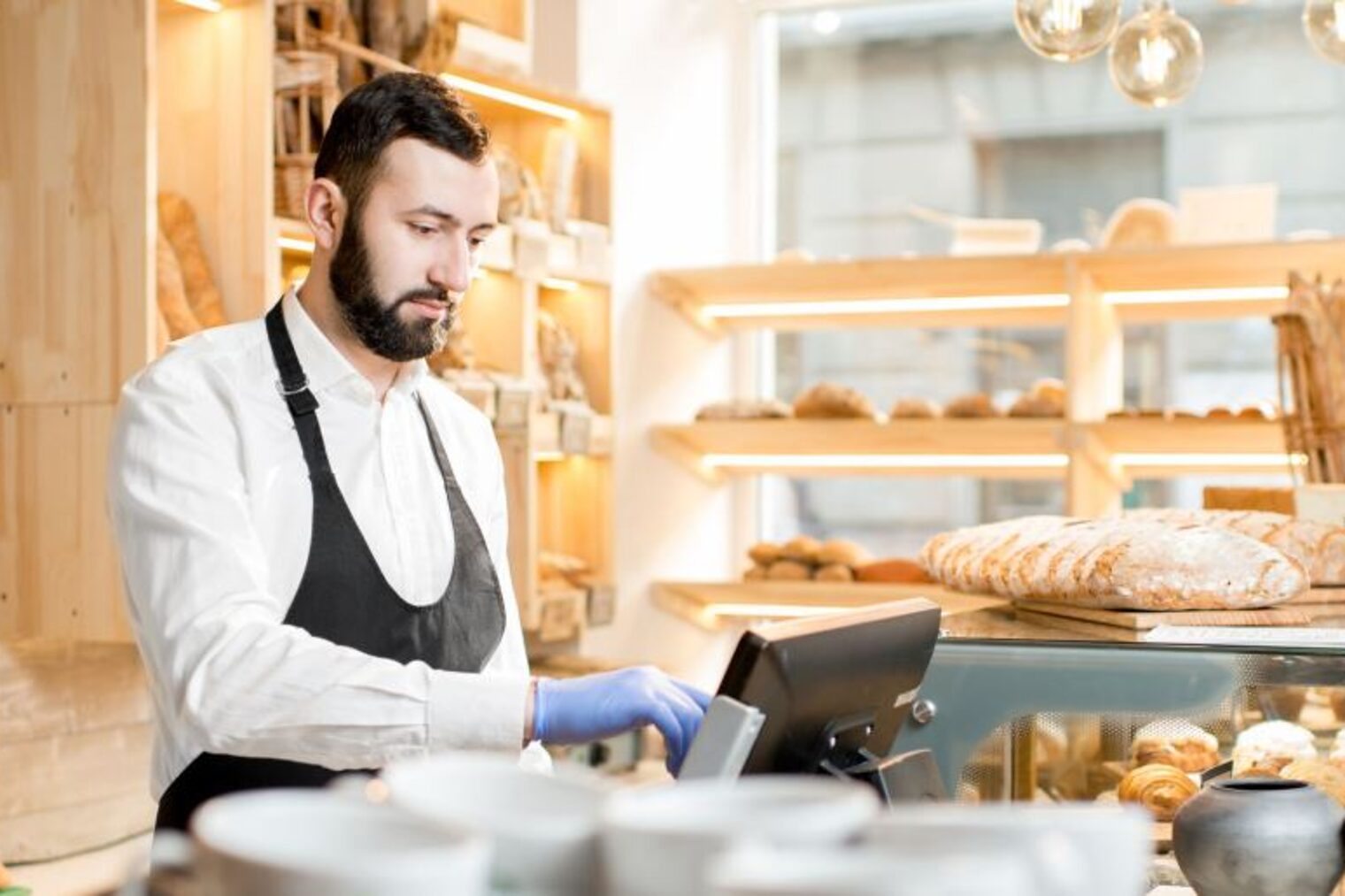 Bäckerei-Verkäufer gibt Geldbetrag in Kassensystem ein.