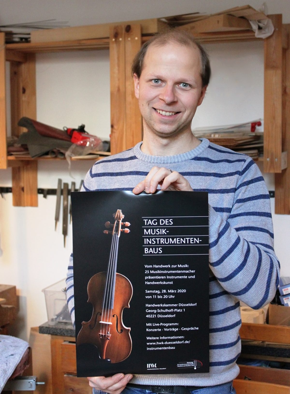 Der Geigenbauer mit eigenem Instrument - auf dem Plakat zum "Tag des Musikinstrumentenbaus"