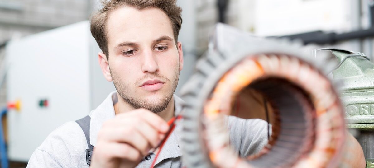 Junger Mann verbindet Kabel an einem Antriebsmotor.