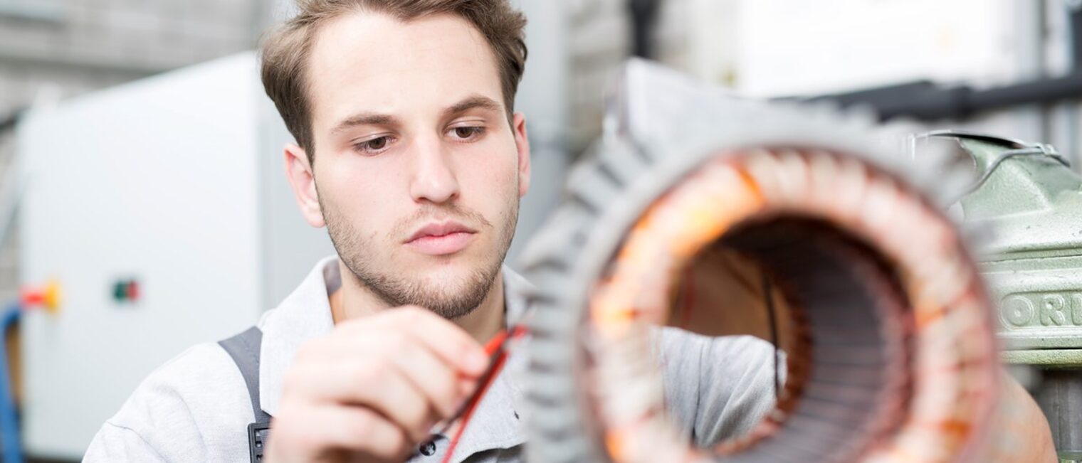 Junger Mann verbindet Kabel an einem Antriebsmotor.