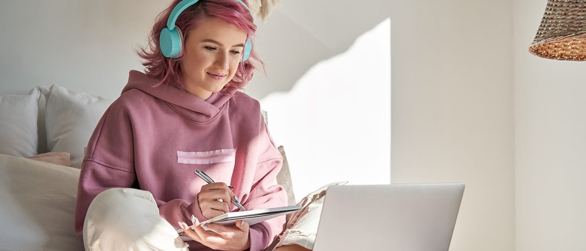Mädchen mit Kopfhörer arbeitet mit Laptop