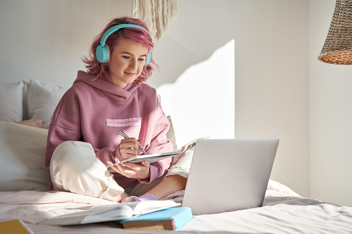 Mädchen mit Kopfhörer arbeitet mit Laptop
