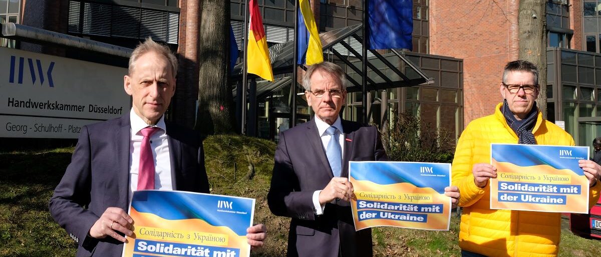 Hauptgeschäftsführer Axel Fuhrmann, Präsident Andreas Ehlert und Knut Koch, Vorsitzender des Personalrats der Handwerkskammer Düsseldorf Kammerspitze vor dem HWK-Gebäude mit Handzetteln "Solidarität mit der Ukraine".