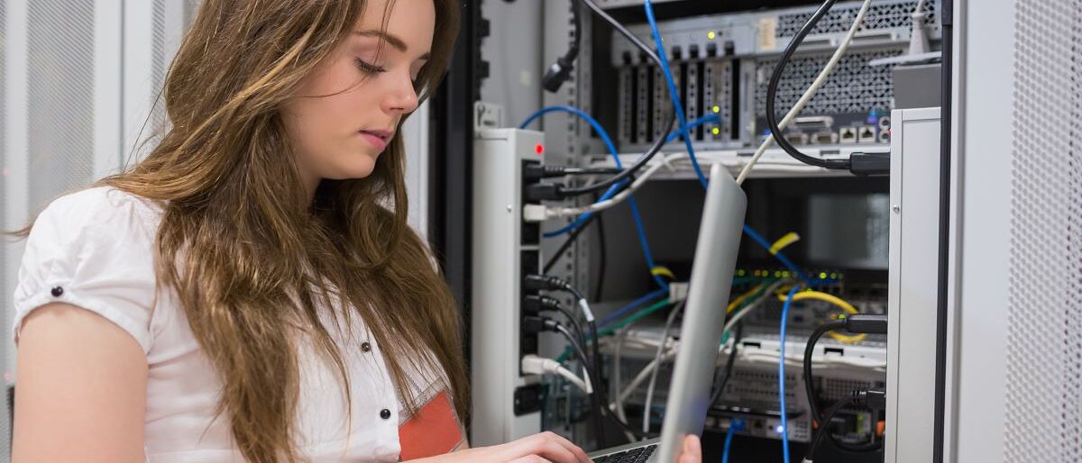 Junge Frau, die Laptop verwendet, um auf Servern im Rechenzentrum zu arbeiten.