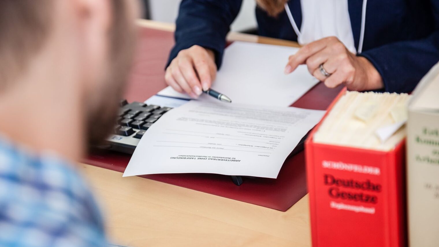 Eine Person erläutert einem Arbeitnehmer den Arbeitsvertrag