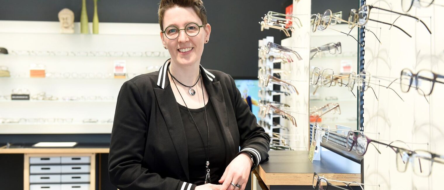Jutta de Buhr steht vor einem Brillenregal