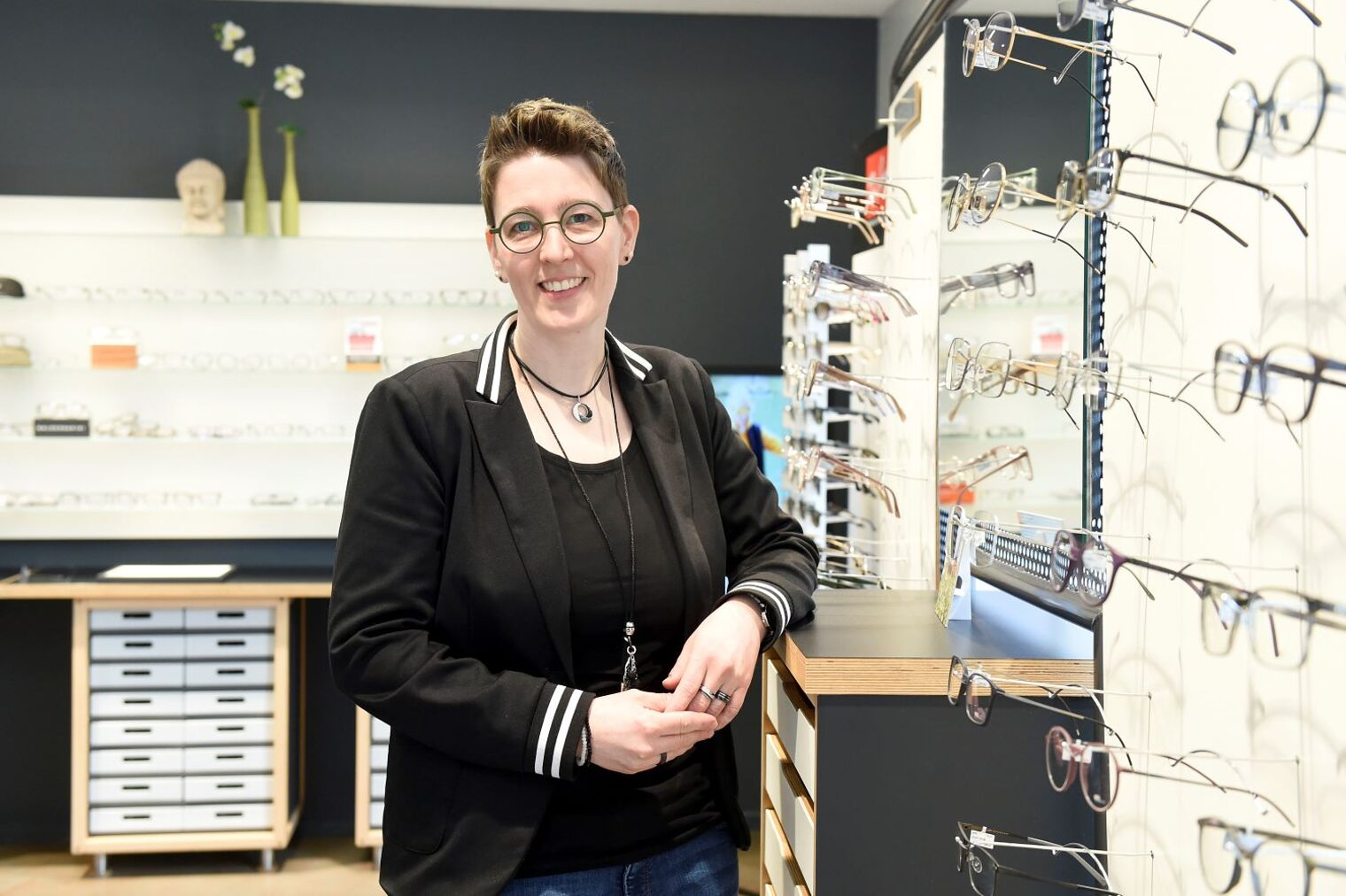 Jutta de Buhr steht vor einem Brillenregal