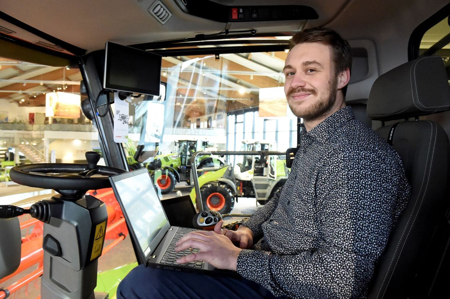 Henrik Eikmeier mit seinem Laptop im Führerstand einer Landmaschine