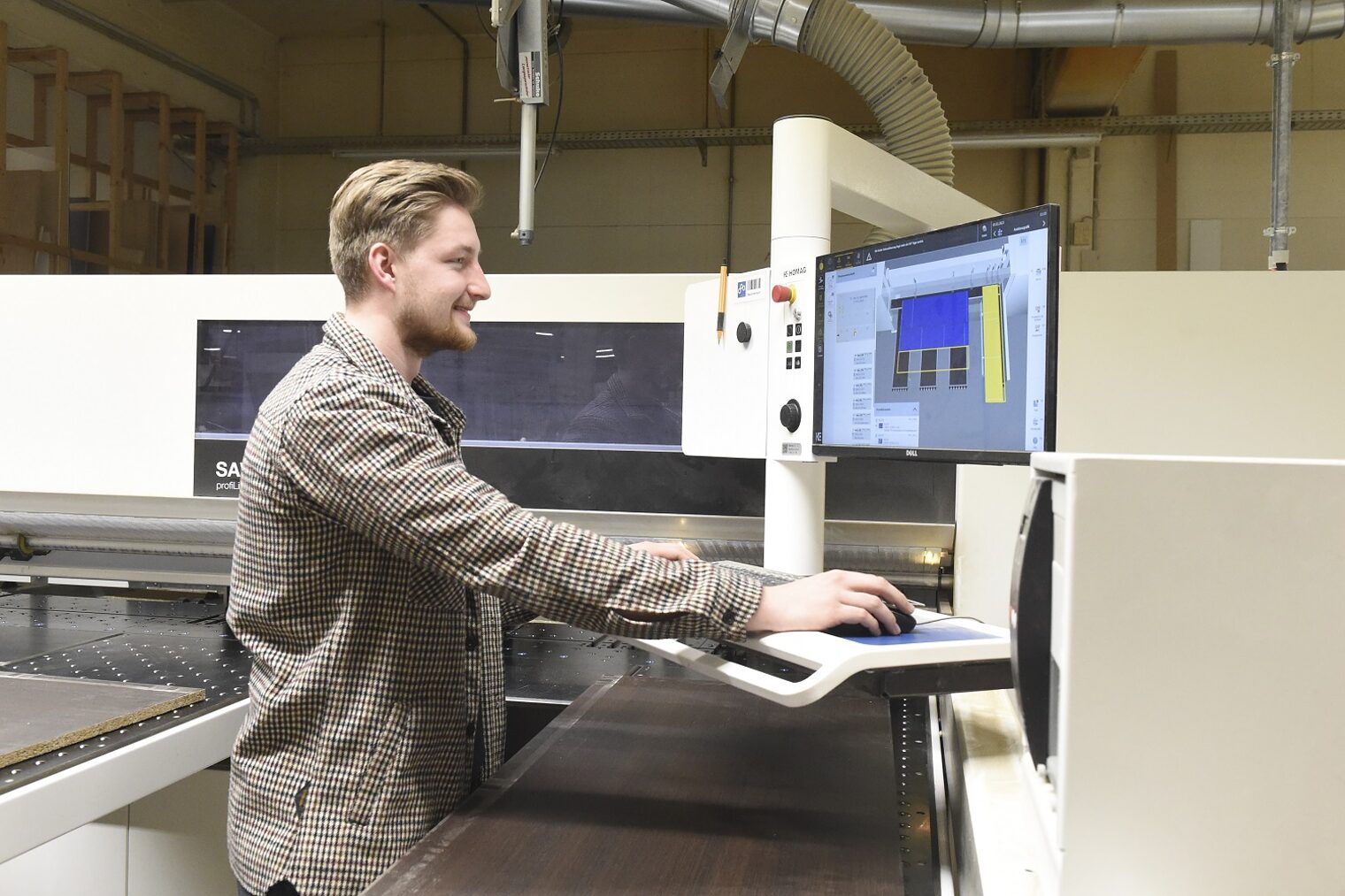 Ein Mann bedient eine moderne Maschine in einer Tischlerwerkstatt.