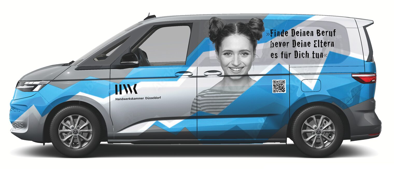 Das Bild zeigt einen VW-Bus mit einer grafischen Beklebung und einer jungen Frau. 