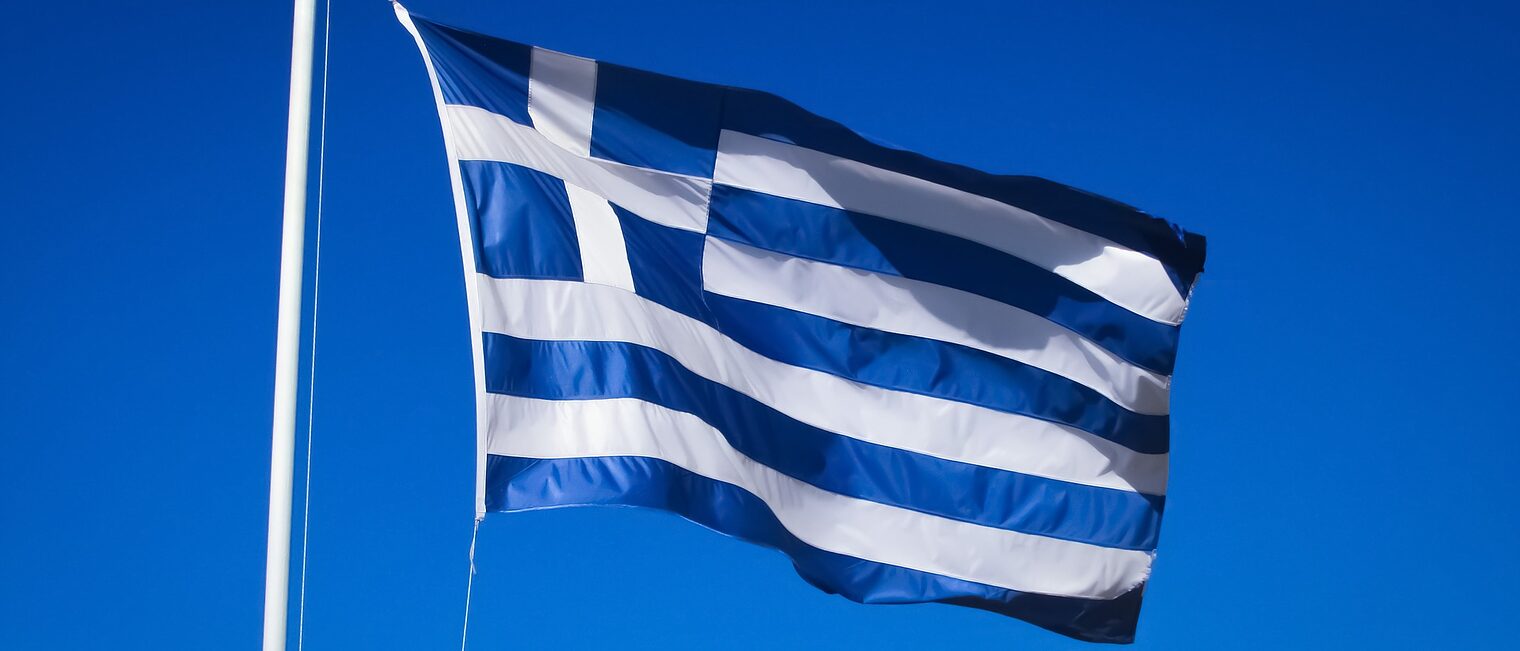 Eine griechische Flagge weht vor dem Himmel.