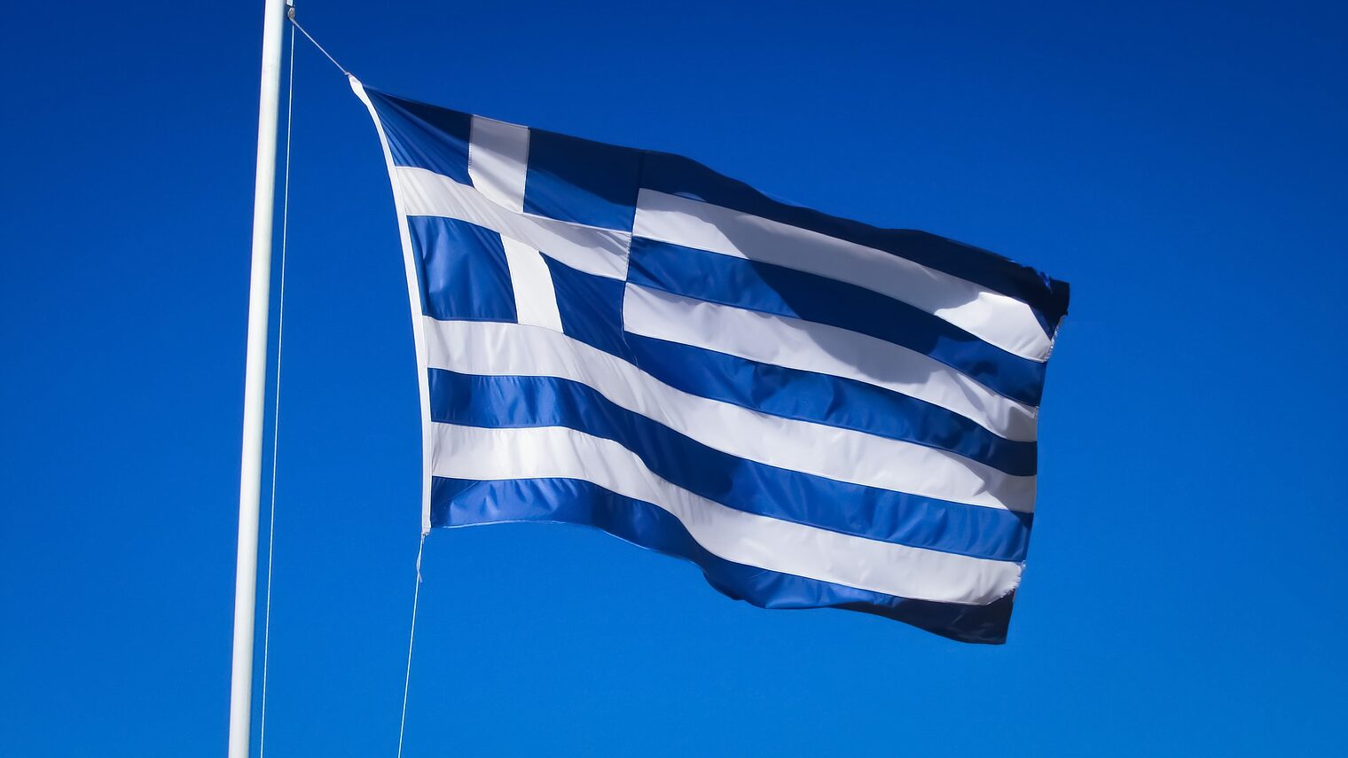 Eine griechische Flagge weht vor dem Himmel.