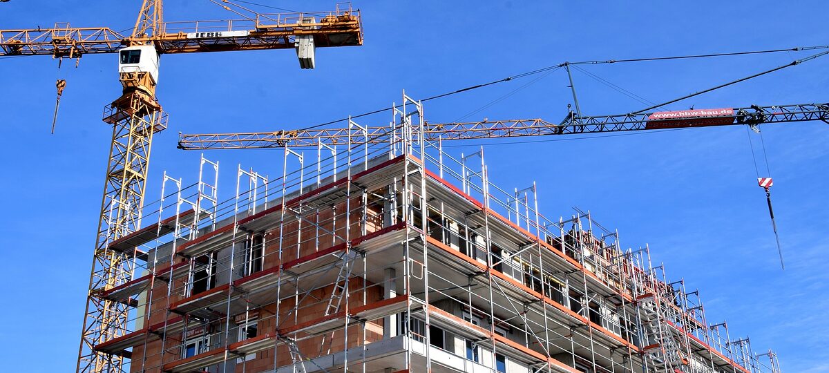 Baustelle eines mehrstöckigen Wohnhauses mit zwei Kränen