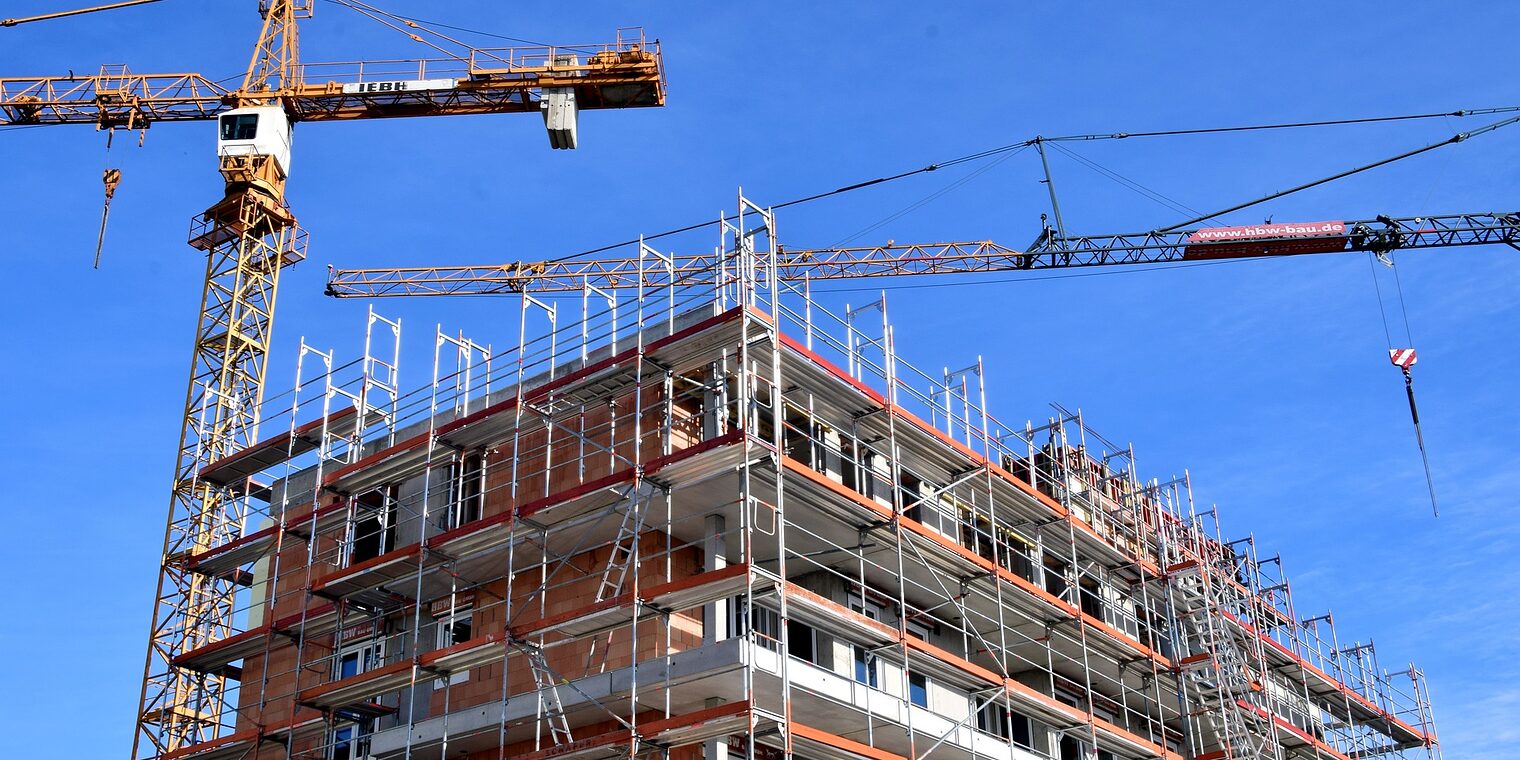 Baustelle eines mehrstöckigen Wohnhauses mit zwei Kränen