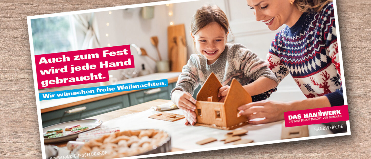 Das Bild zeigt eine Weihnachtskarte, auf der Mutter und Tochter an einem Lebkuchenhaus basteln. Überschrift: Auch zum Fest wird jede Hand gebraucht.