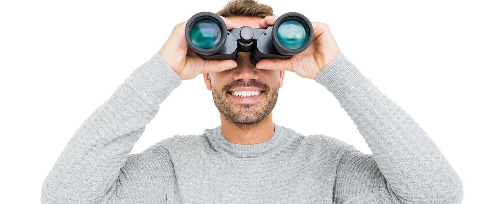 Junger Mann schaut durch ein Fernglas