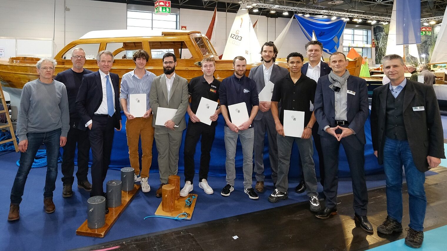 Die Teilnehmer stehen auf der Messe boot 25 vor einem ausgestellten Schiff.