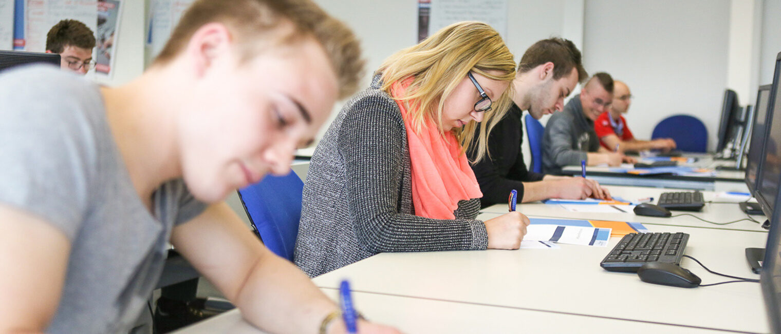 Seminarteilnehmer in einem modernen Schulungsraum Teilnehmer eines Seminars schreiben Notizen an Computertischen