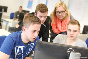 Gruppe von jungen Erwachsenen arbeitet gemeinsam an einem Computer