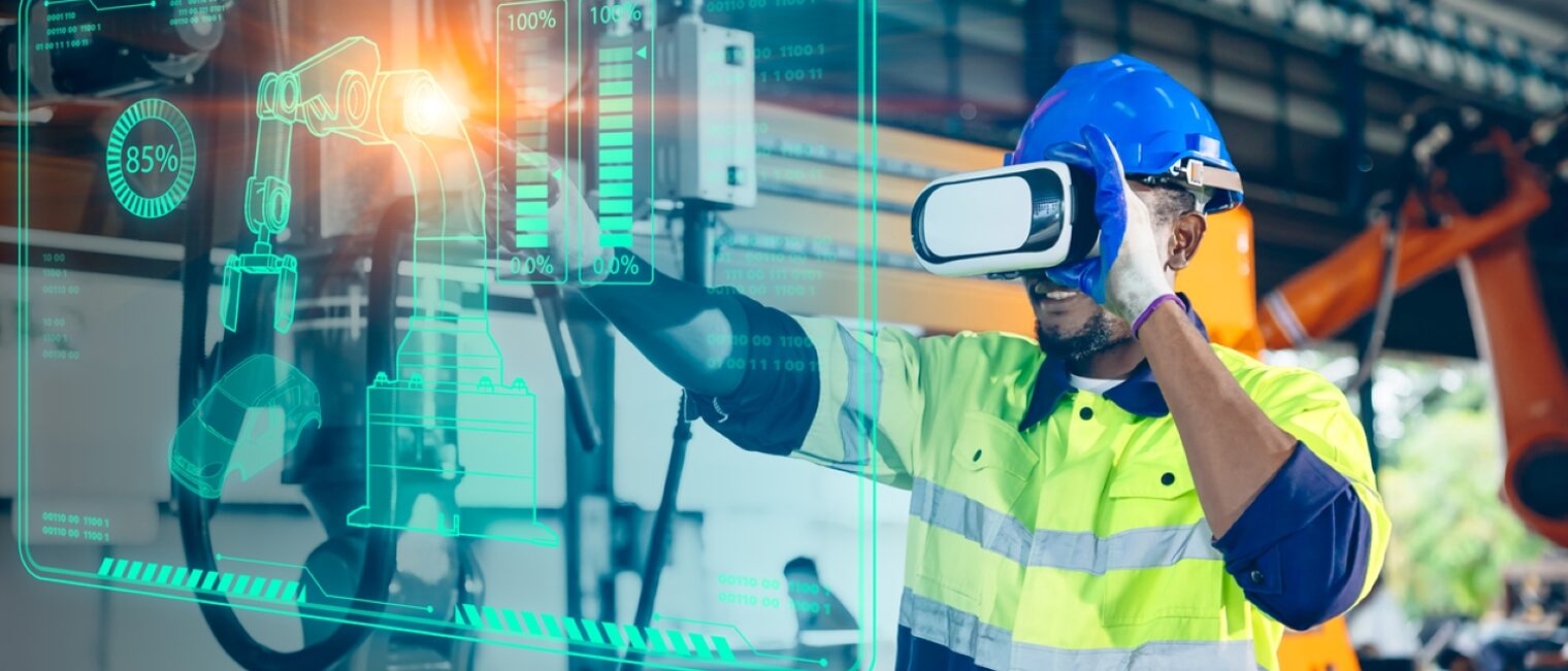 Männlicher Maschinenbauer mit VR-Brille bedient in Werkstatthalle eine Robotermaschine über eine virtuelle Wand.
