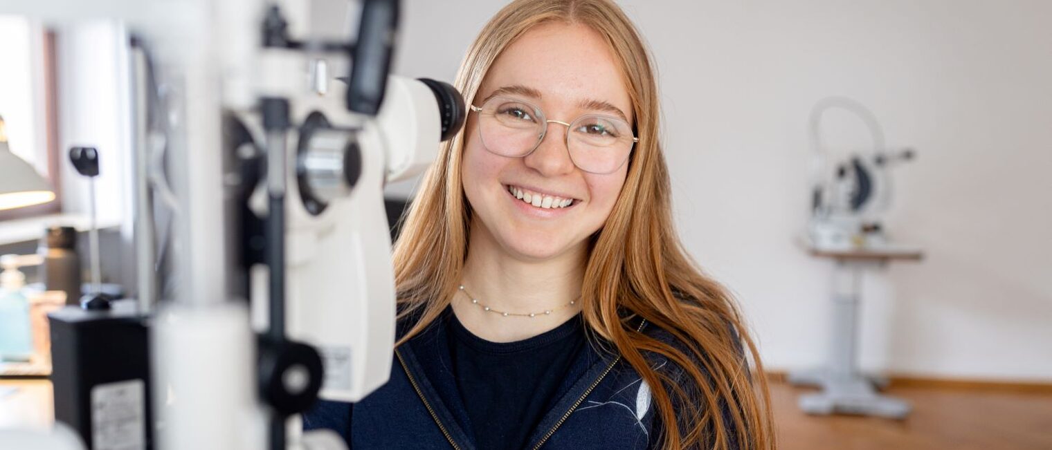 Viktoria Hesselbach steht vor einem Gerät für Augenuntersuchung.