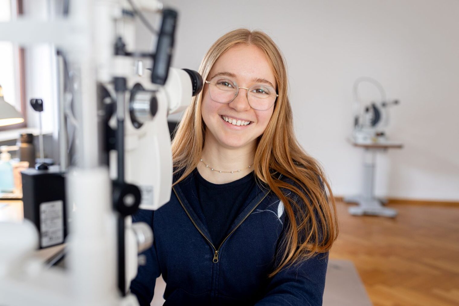 Viktoria Hesselbach steht vor einem Gerät für Augenuntersuchung.