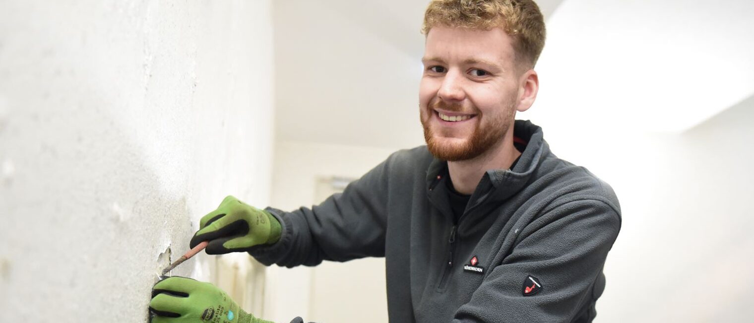 Nils Höpken bei der Arbeit mit Spachtel an einer Wand.