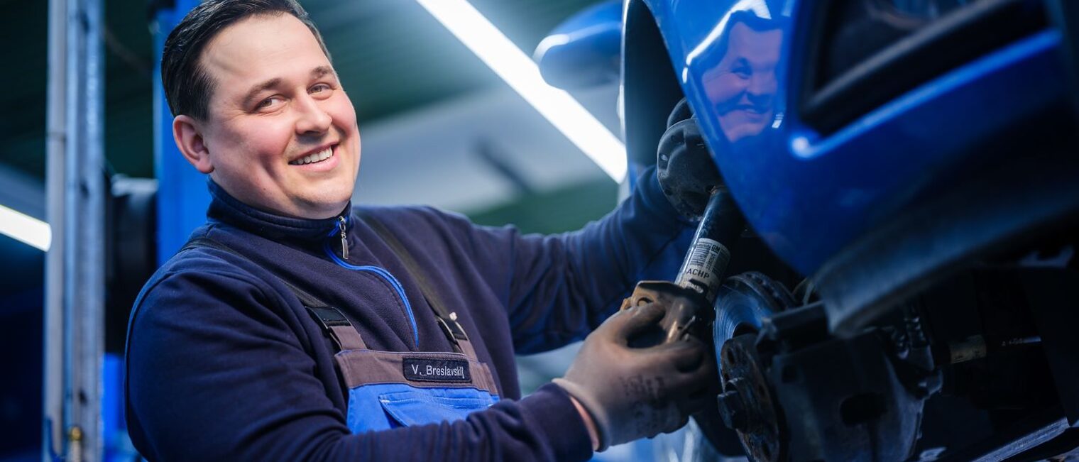 Vadim Breslavskiy arbeitet in einer Werkstatt am Reifen eines aufgebockten Autos.