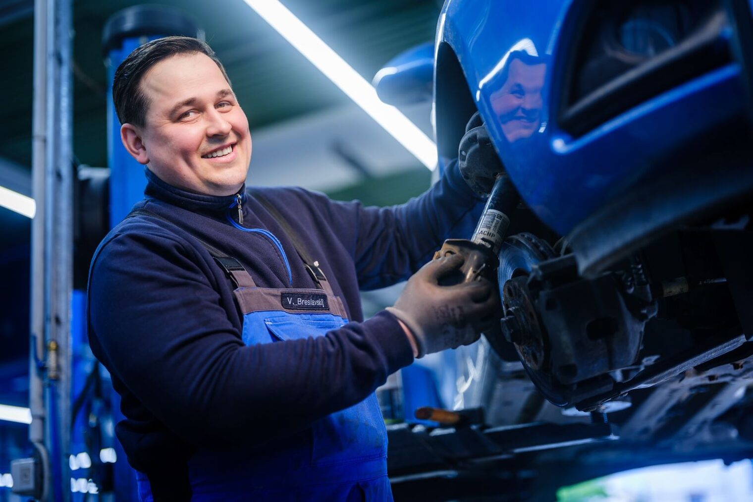 Vadim Breslavskiy arbeitet in einer Werkstatt am Reifen eines aufgebockten Autos.