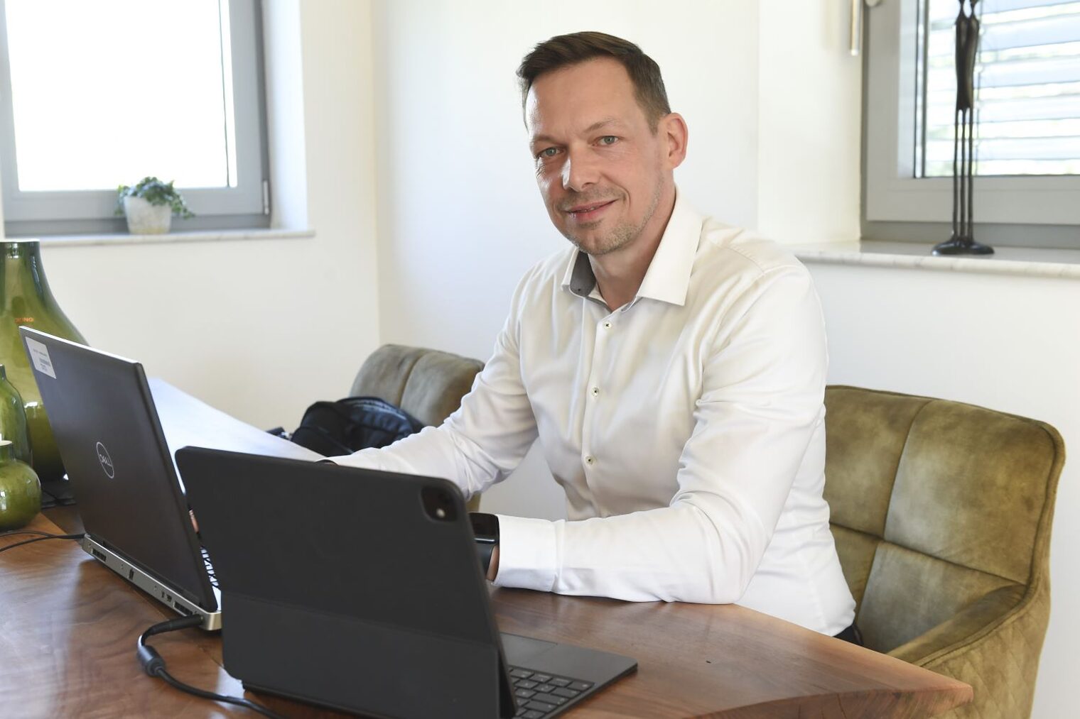 Andre Reichelt sitzt in seinem Büro an einem Schreibtisch. Vor ihm befinden sich zwei Laptops.