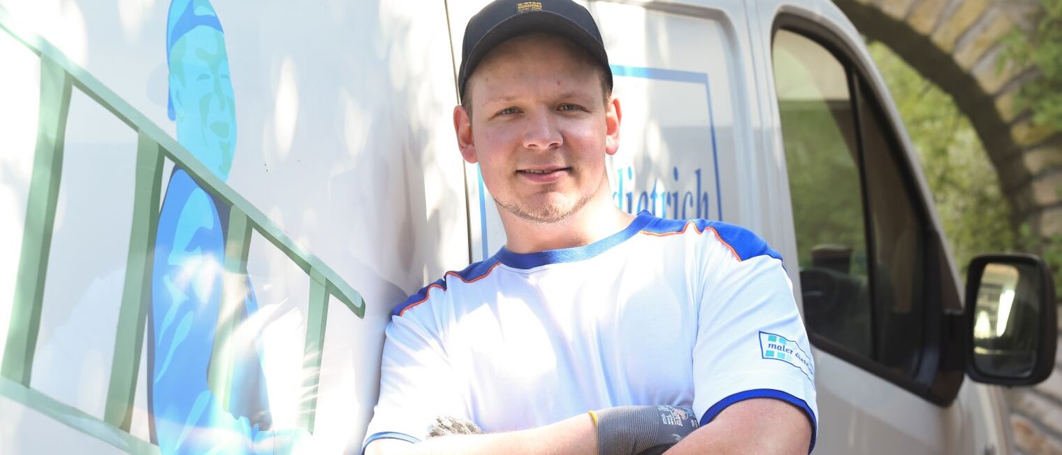 Eric Schmitz lehnt mit verschränkten Armen an einem Transportfahrzeug.