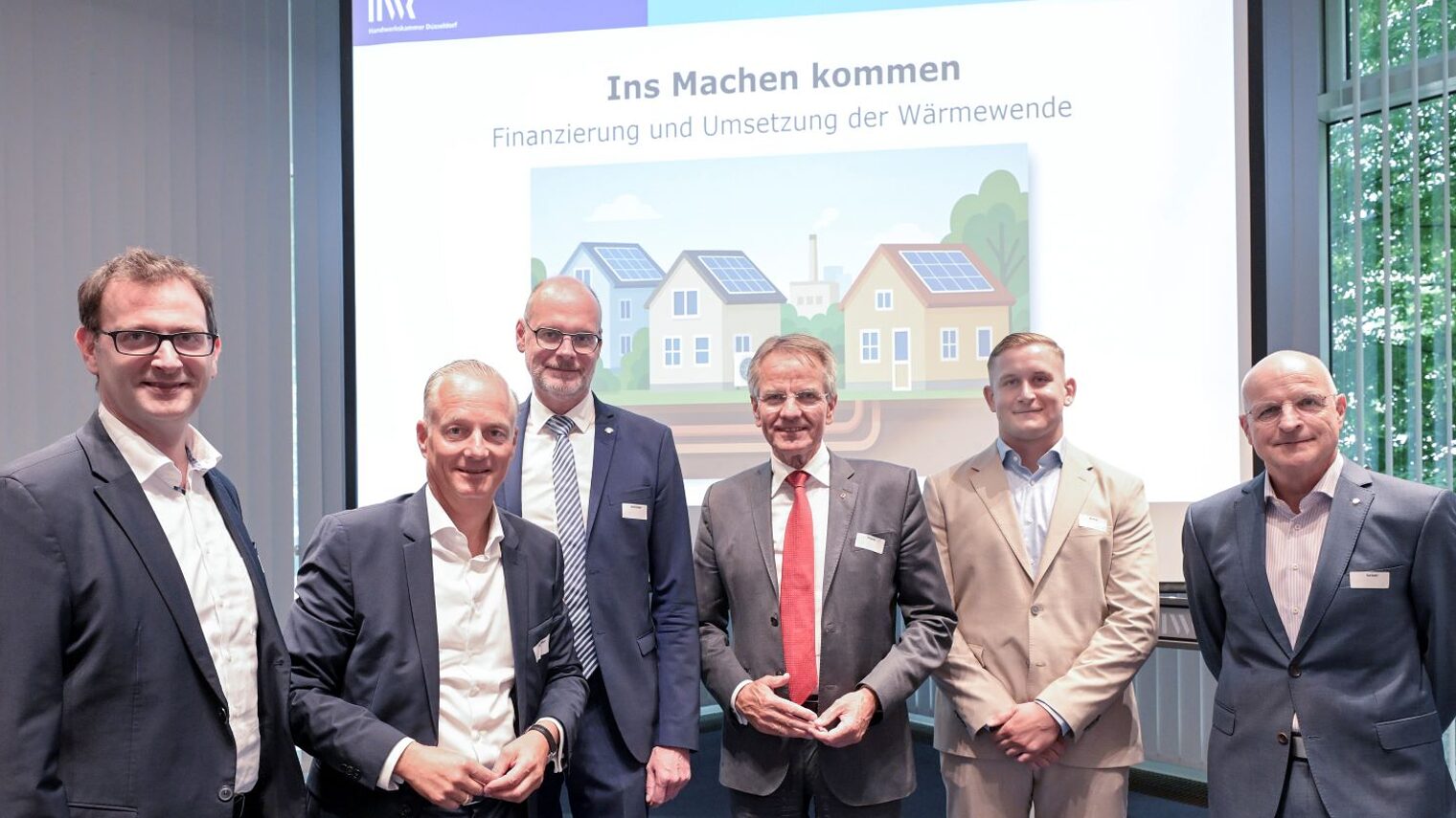Die 4 Podiumsteilnehmer stehen vor einer Beamer-Leinwand, auf der "Ins Machen kommen" steht.