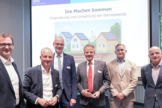 Die 4 Podiumsteilnehmer stehen vor einer Beamer-Leinwand, auf der "Ins Machen kommen" steht.