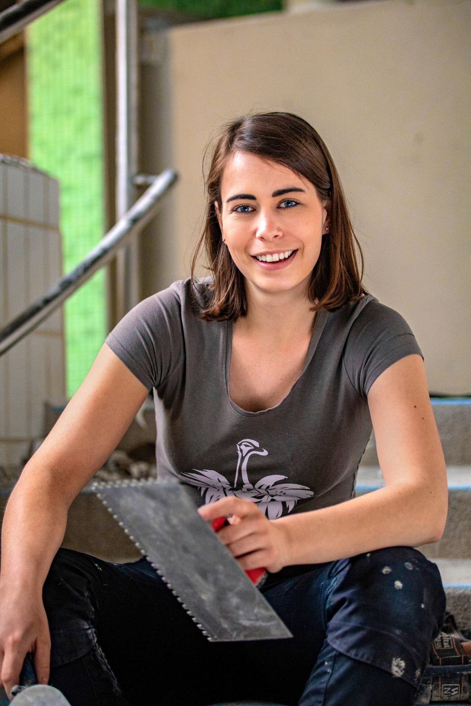 Anne Heidrich mit Fugenkelle in der Hand schaut lachend in die Kamera