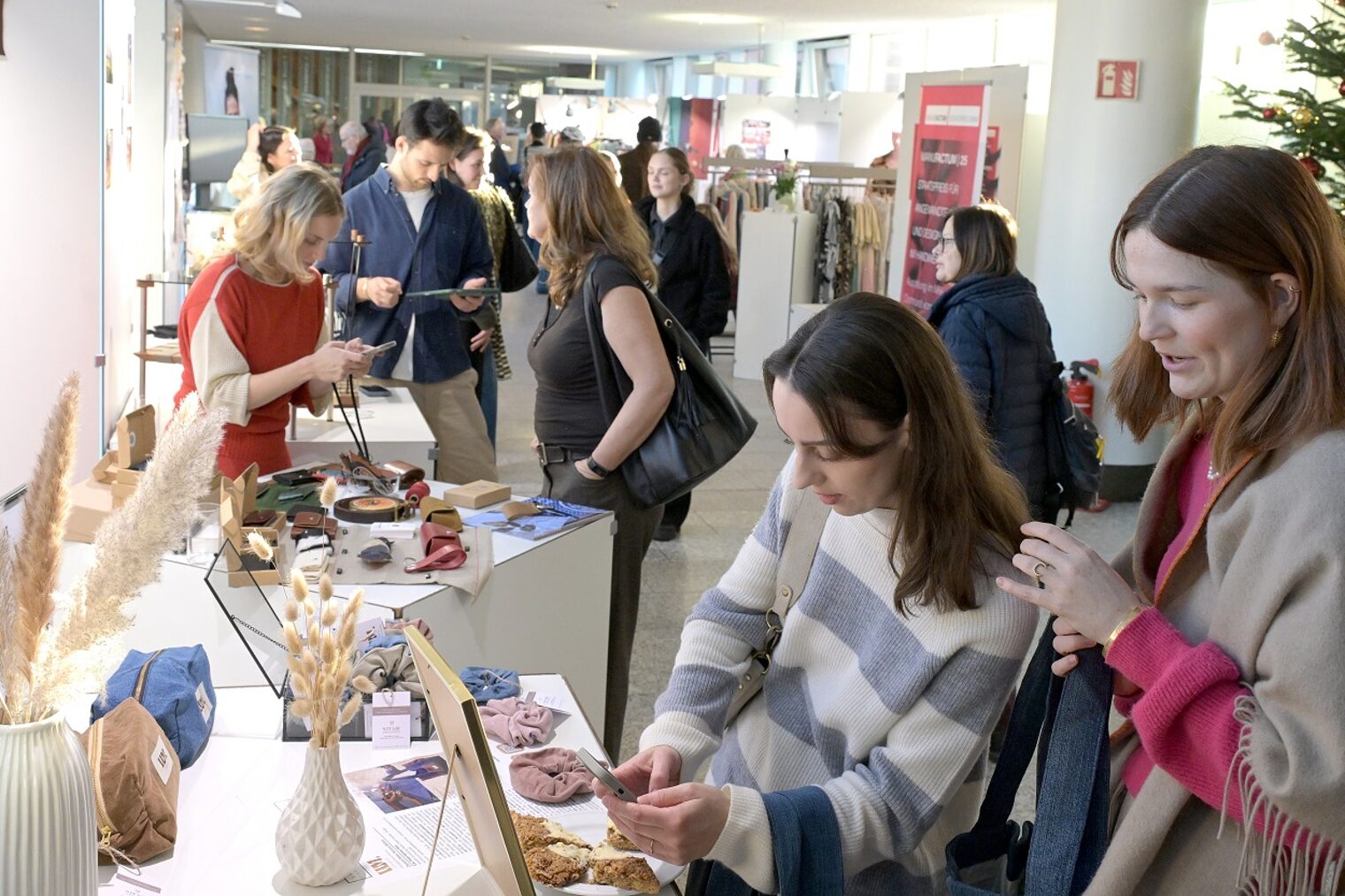 Zwei junge Besucherinnen der Unikate-Ausstellung schauen sich Kunsthandwerk-Objekte an.