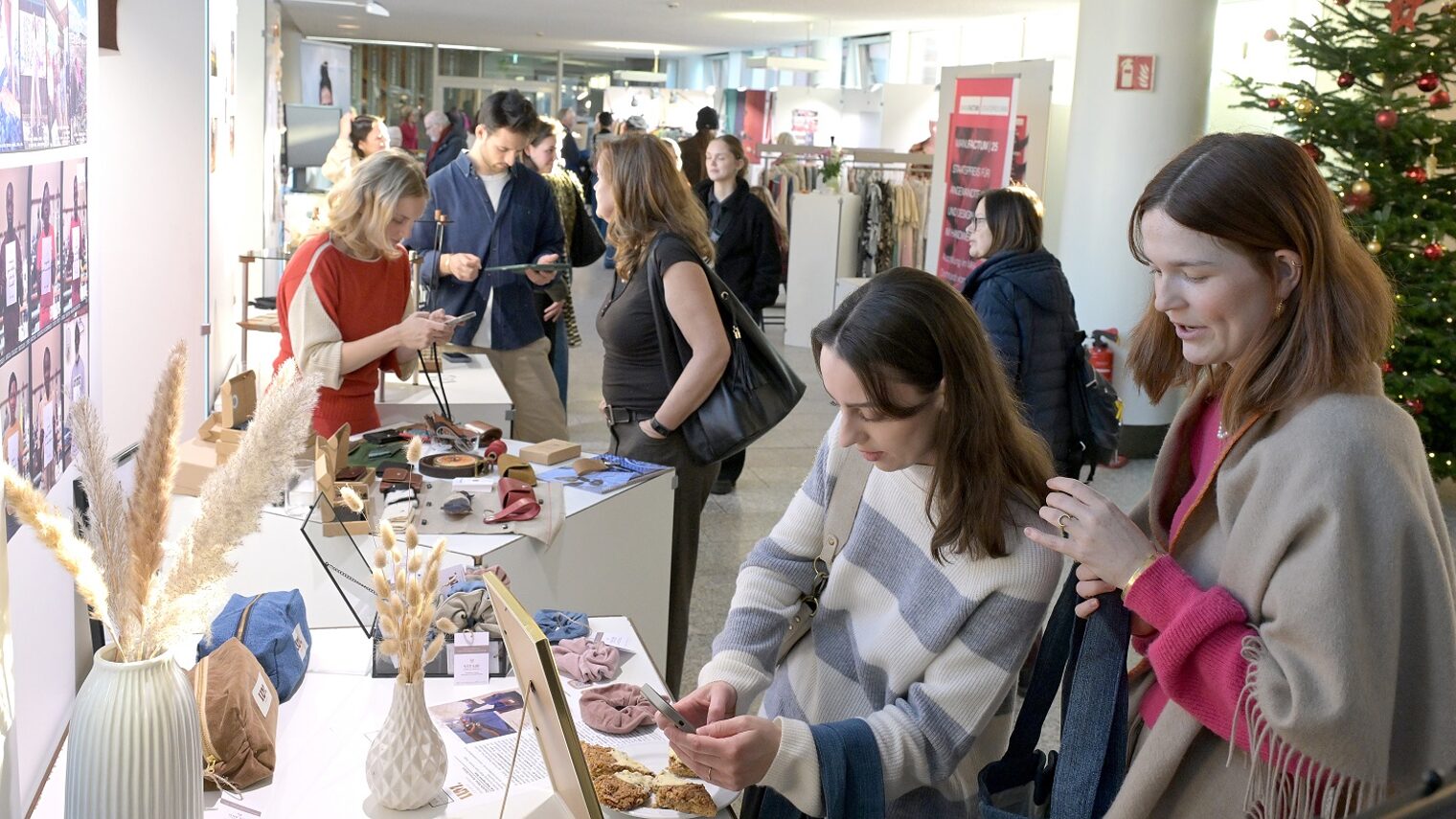 Zwei junge Besucherinnen der Unikate-Ausstellung schauen sich Kunsthandwerk-Objekte an.
