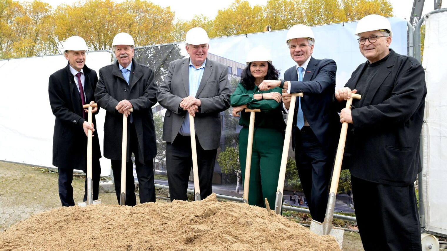 6 Personen aus HWK-Führungspitze und NRW-Ministerium posieren mit ihren Spaten an der Baustelle.