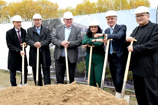 6 Personen aus HWK-Führungspitze und NRW-Ministerium posieren mit ihren Spaten an der Baustelle.