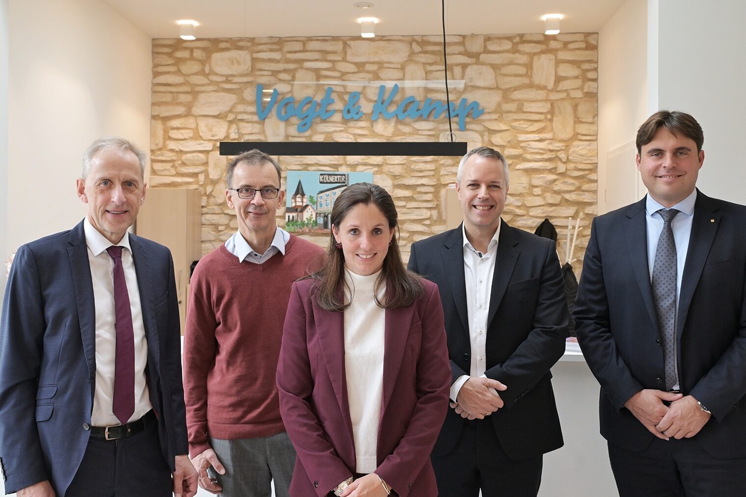 Die Teilnehmer der Pressekonferenz posieren vor einem Hintergrund in Backsteinoptik für ein Pressefoto.