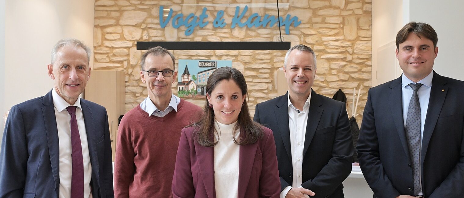 Die Teilnehmer der Pressekonferenz posieren vor einem Hintergrund in Backsteinoptik für ein Pressefoto.
