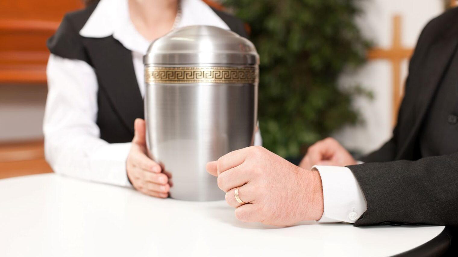 Bestatter in einem Beratungsgespräch. Auf dem Tisch eine Urne.