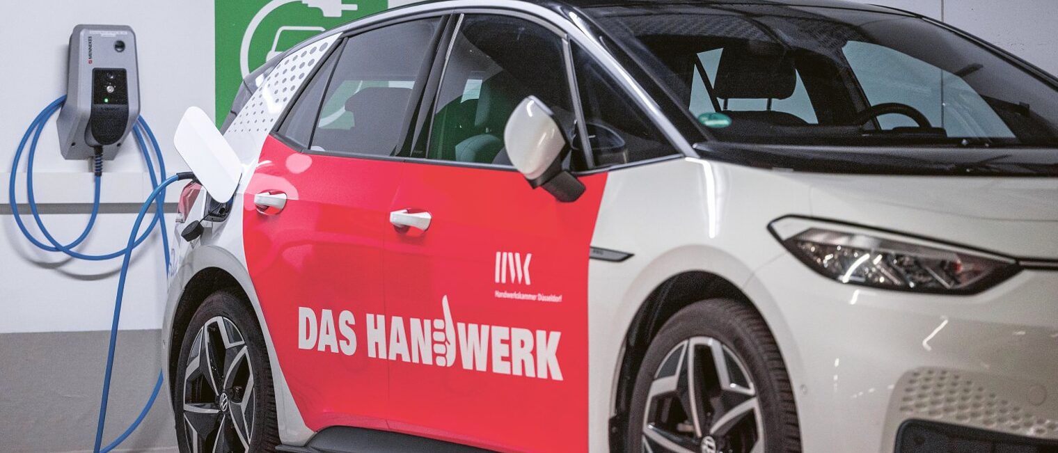Ein PKW mit der Aufschrift "Das Handwerk" wird mit Stromkabel aufgeladen